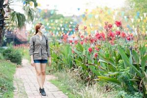 Beautiful traveler girl with mask and backpack walking on road in ayothaya thailand, Travel Holiday Relaxation Concept photo