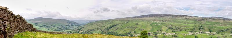 A panoramic of a dry stacked stone wall with a cloudy sky photo