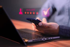 Man's hand using a smartphone and give five star symbol to increase rating of product and service concept, Customer service experience, testimonial and business satisfaction survey. photo