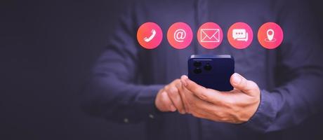 Businessman using mobile phone or smartphone with the call phone, email, address, chat message and map icons. Customer support hotline contact us people connection concept. photo