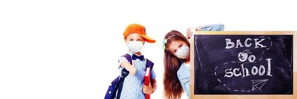 niños pequeños con máscaras de protección contra el virus de la corona en la escuela. foto