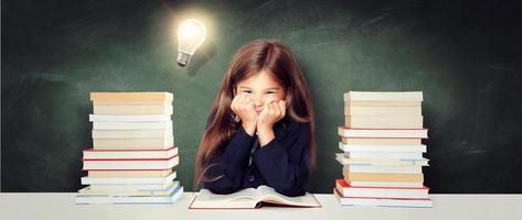 Young cute girl at chalkboard with light bulb over head photo