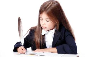 feliz y linda colegiala adolescente escribe en un libro o cuaderno foto