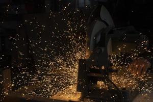 Sparks from metal. Cutting steel. Saw spins quickly. Industrial background. photo