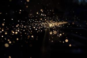 Sparks in dark. Stream of lights on black background. Metal crushing. High temperature. photo