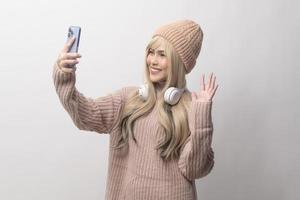 Portrait of Caucasian young woman wearing sweater holding smart phone   over white background photo