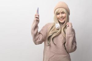 Portrait of Caucasian young woman wearing sweater holding smart phone   over white background photo