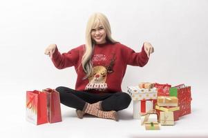 Portrait of happy Caucasian young woman in in Christmas sweater with gift box and shopping bags over white background photo