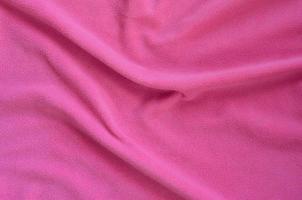 The blanket of furry pink fleece fabric. A background of light pink soft plush fleece material with a lot of relief folds photo