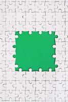 Framing in the form of a rectangle, made of a white jigsaw puzzle around the green space photo