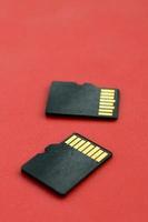 dos pequeñas tarjetas de memoria micro sd se encuentran sobre un fondo rojo. un pequeño y compacto almacén de datos e información foto