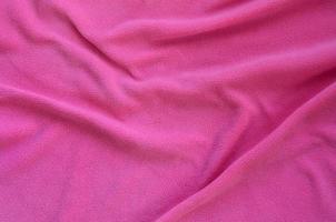 The blanket of furry pink fleece fabric. A background of light pink soft plush fleece material with a lot of relief folds photo