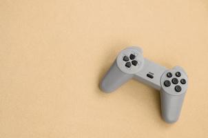 Playing games concept. Single pad joystick lies on the blanket of furry orange fleece fabric. Controller for video games on a background texture of light orange soft plush fleece material photo