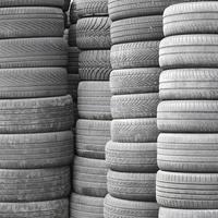 Old used tires stacked with high piles in secondary car parts shop garage photo