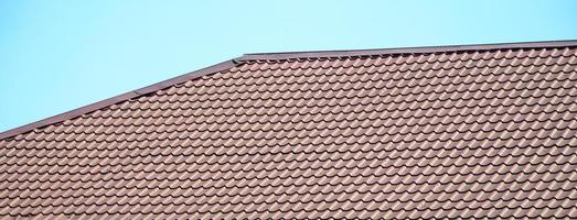 A fragment of a roof from a metal tile of dark red color. Quality Roofing photo