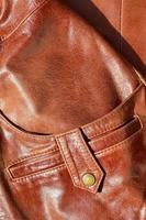 Brown leather texture. Useful as background for any design work. Macro photo of a button on outer clothing made of genuine leather