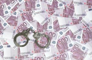 Handcuffs on five hundred euros background. Financial crime, dirty money and corruption concept - 500 money bills and dirty steel handcuffs photo