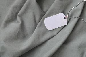 Silvery military beads with dog tag on dark green private fatigue uniform photo