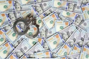 Silver police handcuffs lies on a many dollar bills photo