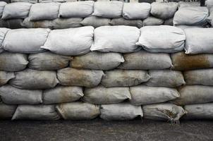 Background of many dirty sand bags for flood defense. Protective sandbag barricade for military use. Handsome tactical bunker photo