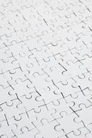Close up of a white jigsaw puzzle in assembled state in perspective. Many components of a large whole mosaic are united photo