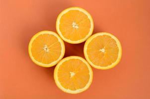Top view of a several orange fruit slices on bright background in orange color. A saturated citrus texture image photo
