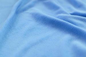 The blanket of furry blue fleece fabric. A background of light blue soft plush fleece material with a lot of relief folds photo
