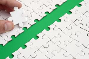 The human hand paves the way to the surface of the jigsaw puzzle, forming a green space. The concept of overcoming the difficulties on the way to success photo
