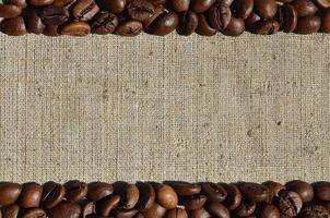 Texture of a gray canvas made of old and coarse burlap with coffee beans on it photo