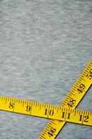 Yellow measuring tape lies on a gray knitted fabric photo