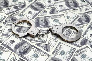 Police handcuffs lie on a lot of dollar bills. The concept of illegal possession of money, illegal transactions with US dollars. Economic Crime photo