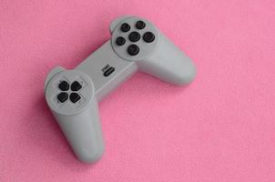 concepto de juegos. El joystick de una sola almohadilla se encuentra sobre la manta de tela de lana rosa peluda. controlador para videojuegos en una textura de fondo de material de vellón de felpa suave rosa claro foto