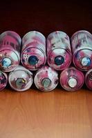 Bodegón con un gran número de latas de aerosol de colores usadas sobre la superficie de madera tratada en el taller de graffiti del artista. latas sucias y manchadas para spray art foto