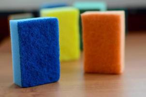 A few kitchen sponges lie on a wooden kitchen countertop. Colorful objects for washing dishes and cleaning in the house are ready for use photo