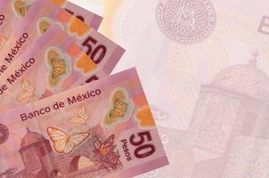 Los billetes de 50 pesos mexicanos se encuentran apilados sobre el fondo de un gran billete semitransparente. fondo de negocios abstracto foto