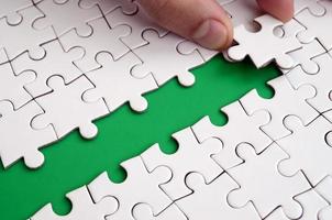 The human hand paves the way to the surface of the jigsaw puzzle, forming a green space. The concept of overcoming the difficulties on the way to success photo