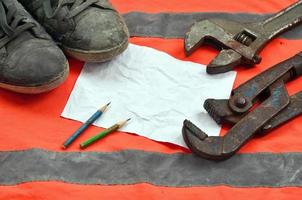 Adjustable wrenches with old boots and a sheet of paper with two pencils photo