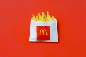 KHARKOV, UKRAINE - DECEMBER 9, 2020 McDonald's French fries in small paperbag on bright red background photo