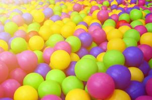 muchas bolas de plástico de colores en una piscina para niños en un parque infantil. patrón de primer plano foto