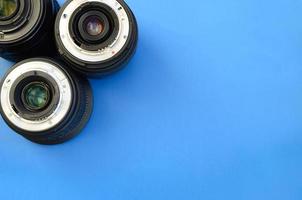 Several photographic lenses lie on a bright blue background. Space for text photo