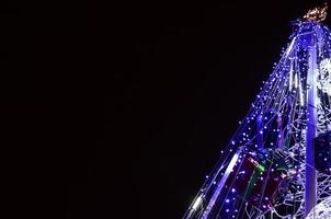 fragmento del árbol de año nuevo. muchas luces redondas de color azul están ubicadas en un marco cónico foto