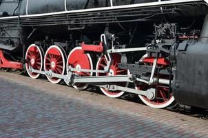 Wheels of the old black steam locomotive of Soviet times. The side of the locomotive with elements of the rotating technology of old trains photo