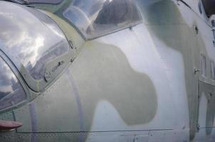 Helicopter cabin fragment close up. Camouflage aircraft fuselage and bulletproof glass photo