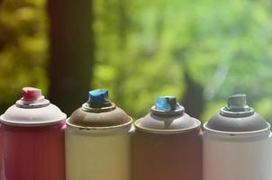 A few used aerosol paint sprayers lie on the windowsill in the workshop of a graffiti artist. The concept of street art and illegal drawing on the walls. Youth hobby photo