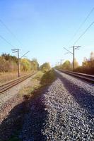 Autumn industrial landscape. Railway receding into the distance among green and yellow autumn trees photo