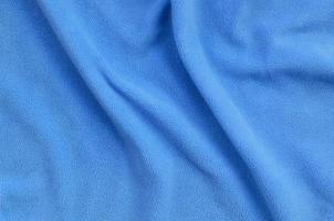 The blanket of furry blue fleece fabric. A background of light blue soft plush fleece material with a lot of relief folds photo