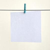 White blank cards on rope, light wall background. Creative reminder, small sheets of paper on old clothespin, memo backdrop photo