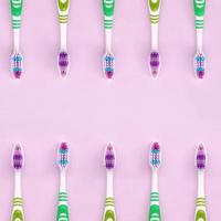 muchos cepillos de dientes yacen sobre un fondo rosa pastel foto