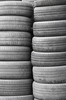 Old used tires stacked with high piles in secondary car parts shop garage photo