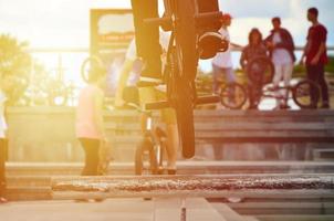 un ciclista salta sobre una tubería en una bicicleta bmx. mucha gente con bicicletas en el fondo. concepto de deportes extremos foto